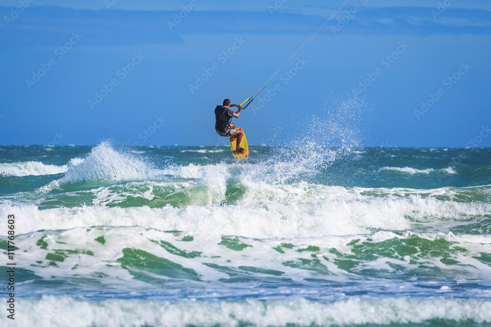 Athletic man riding on kite surf board at sea waves Athletic man riding on kite surf board at sea waves