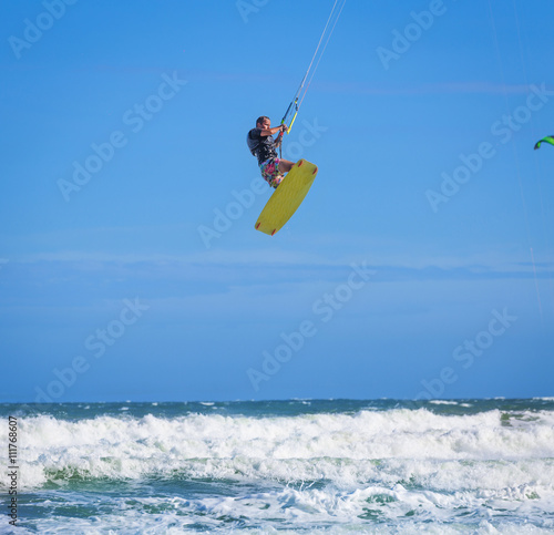 Athletic man riding on kite surf board at sea waves
