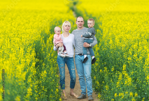 Happy family have a rest on the yellow rape field.