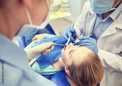 close up of dentist treating female patient teeth