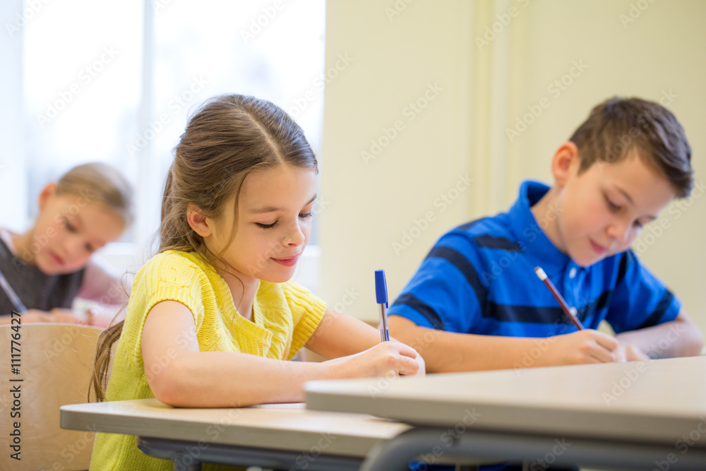 group of school kids writing test in classroom group of school kids writing test in classroom