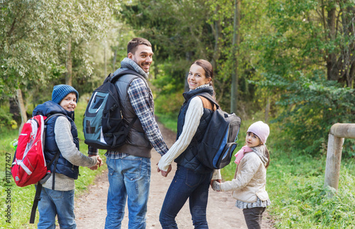 happy family with backpacks hiking in woods