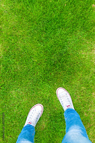 Feet in sneakers on green grass