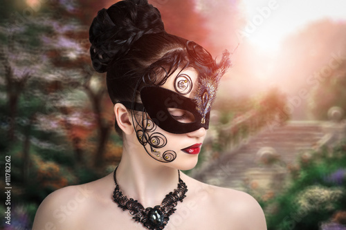 Beautiful young girl in a black mask, magic stranger, the mysterious lady, queen of spades. Hair stuck in spirals on the face. New fantastic world of imagination, dream, desire. Conceptual art make-up
