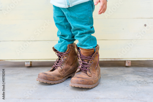 Baby boy try to  wearing father's boots