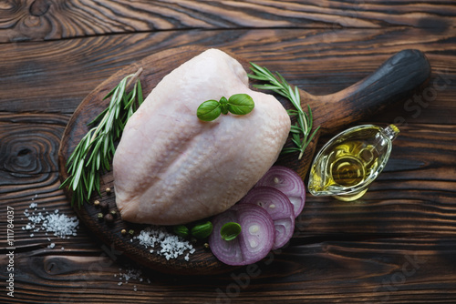 Raw chicken breast and condiments in a rustic wooden setting