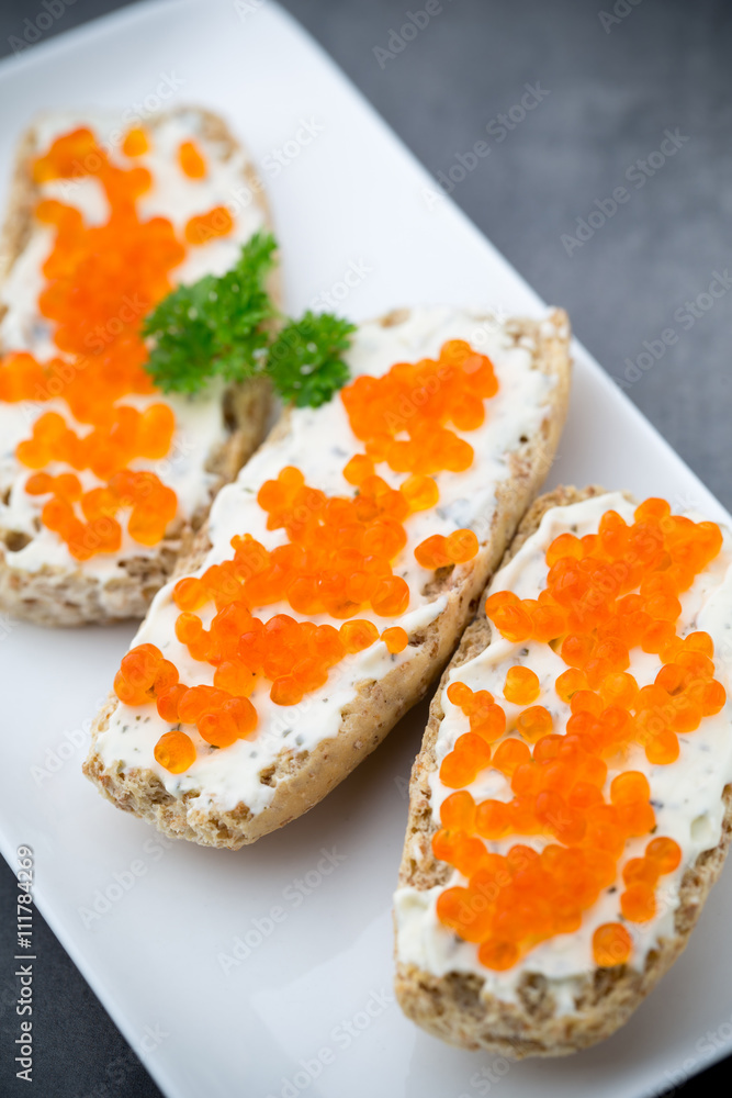 Red caviar on bread on white plate. Red caviar on bread on white plate.