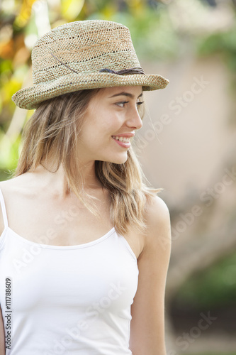 Portrait of a beautiful woman wearing a hat standing in the summer park. Beauty, fashion