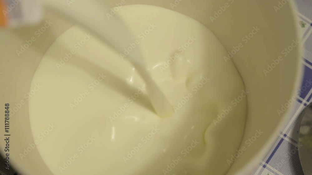 Adding of milk on the bowl to be mixed by a hand mixer Adding of milk on the bowl to be mixed by a hand mixer