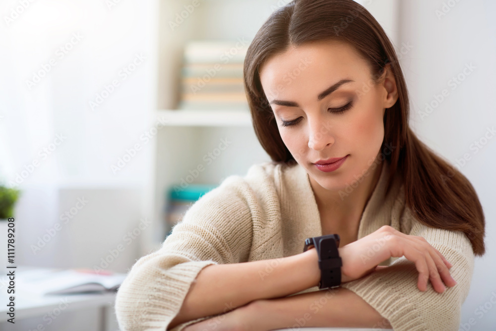 Pleasant woman looking at her watch Pleasant woman looking at her watch