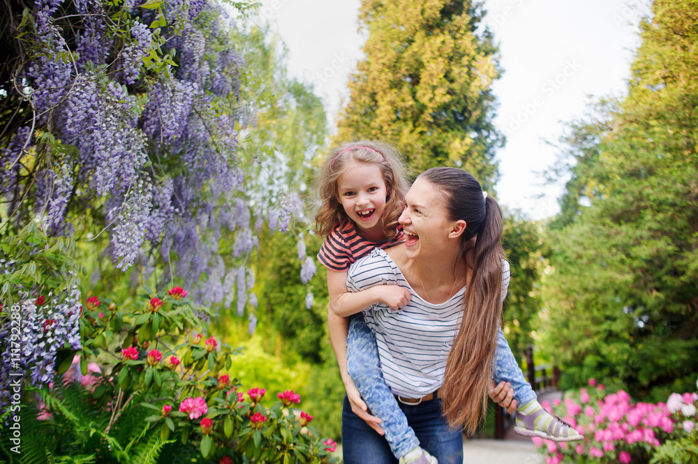 Young woman with a little girl in the flowered garden. Young woman with a little girl in the flowered garden.