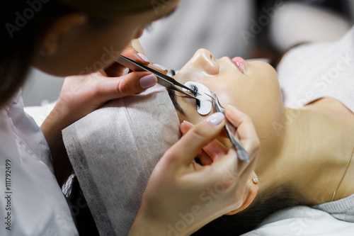 eyelash extension procedure - master and a client in a beauty salon