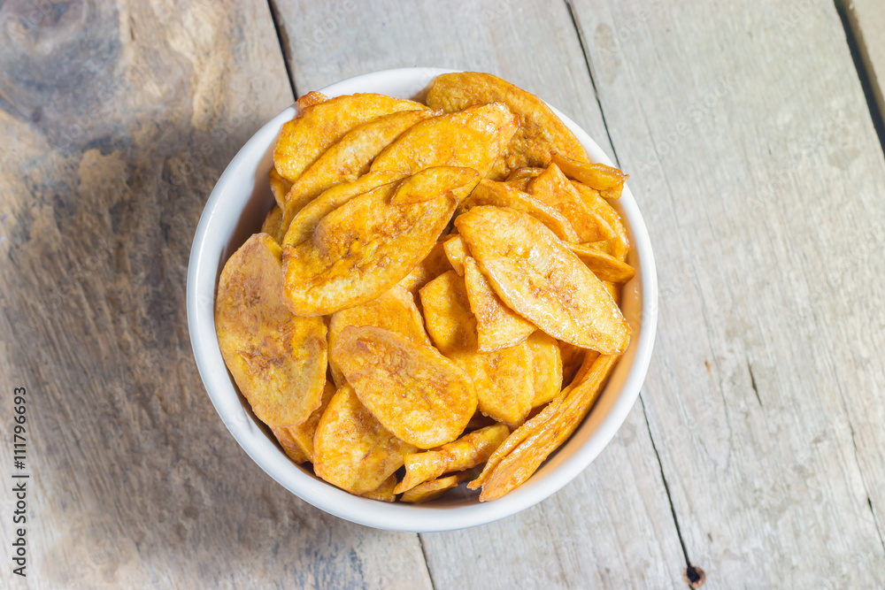 Homemade Banana Chips Baked with honey on wood table Homemade Banana Chips Baked with honey on wood table