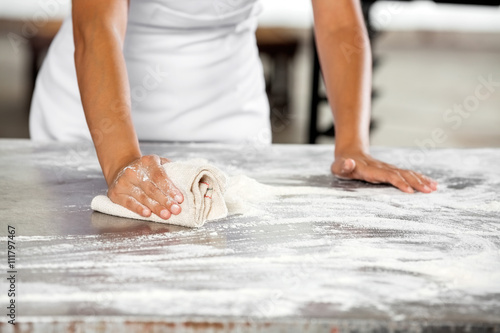Midsection Of Baker Cleaning Flour From Table © Tyler Olson