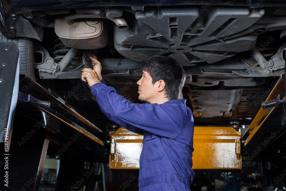 Mechanic Examining Underneath Lifted Car