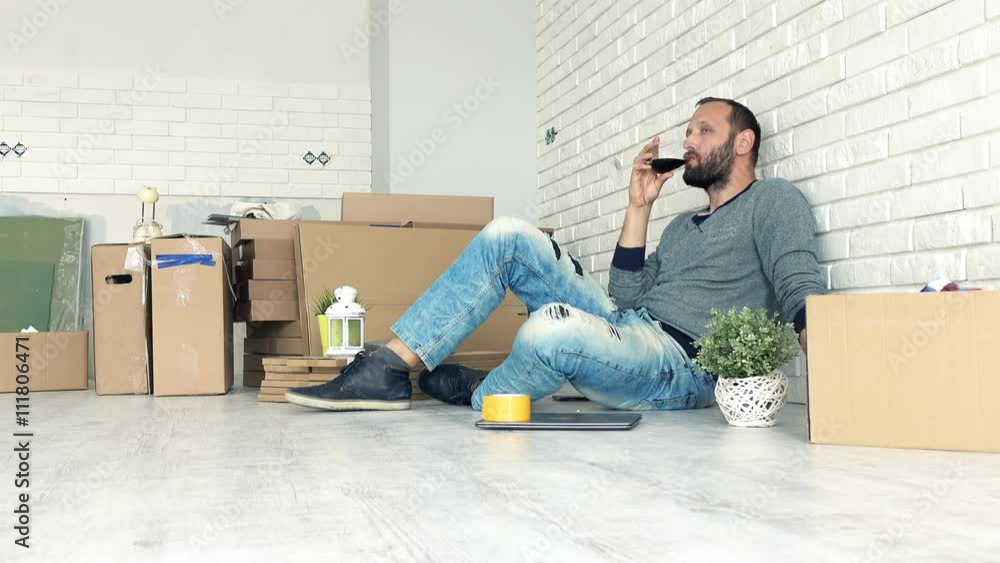 Young man drinking red wine sitting on floor at his new home
Young man drinking red wine sitting on floor at his new home