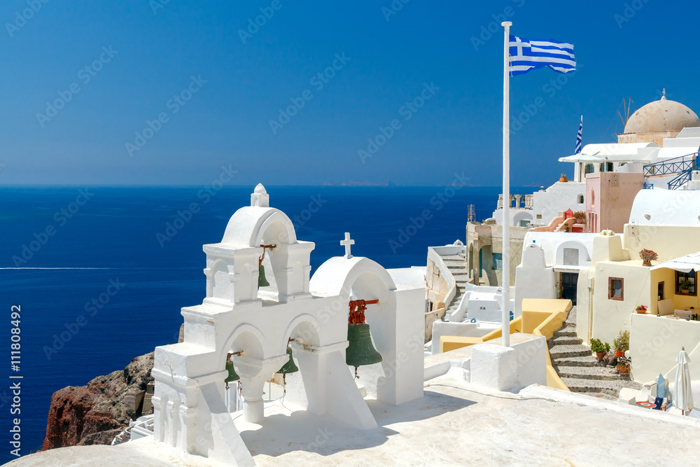 White bell tower and Greek flag in Oia.
