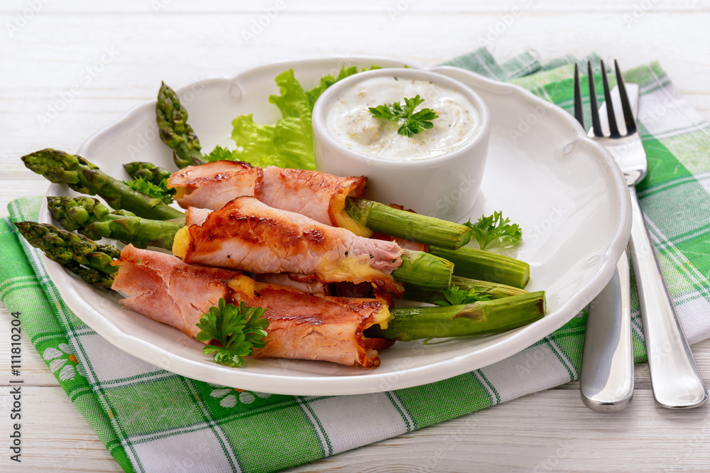 Green asparagus grilled with ham and cheese, served with garlic sauce. Green asparagus grilled with ham and cheese, served with garlic sauce.