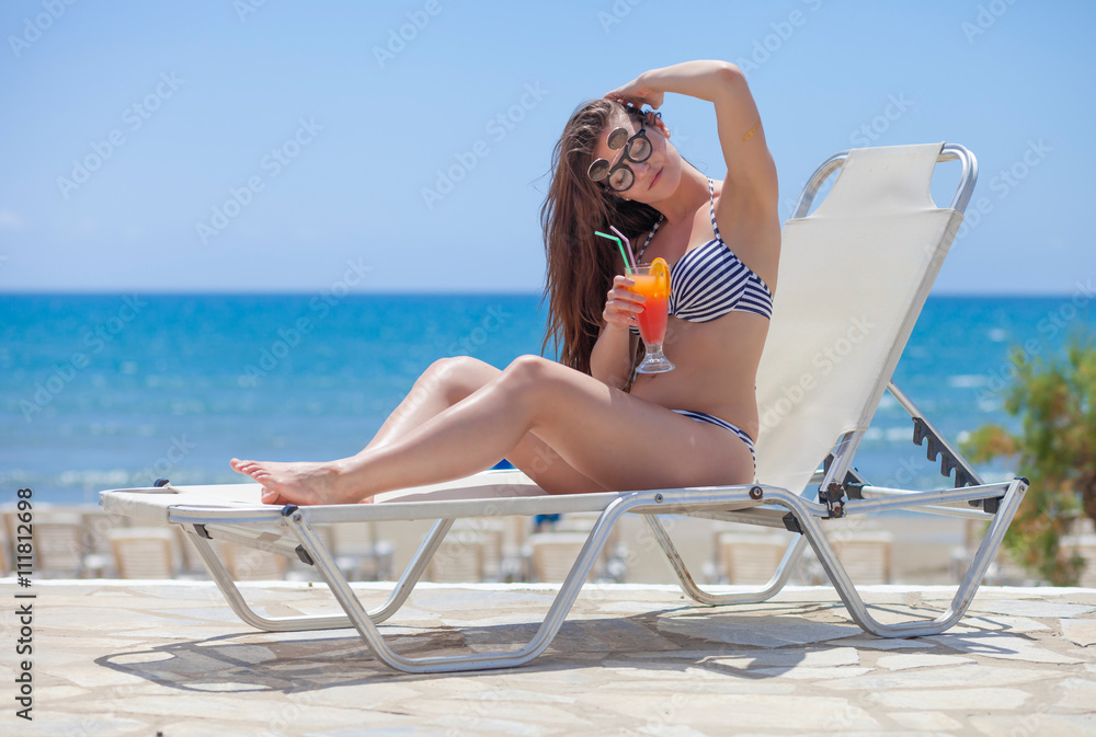 Woman with cocktail during sunbathing on a summer day in the tropics