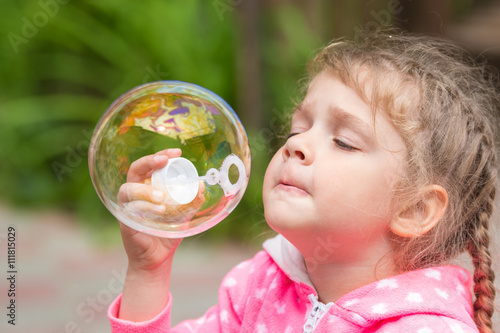 Five-year girl inflates a large circular bubble