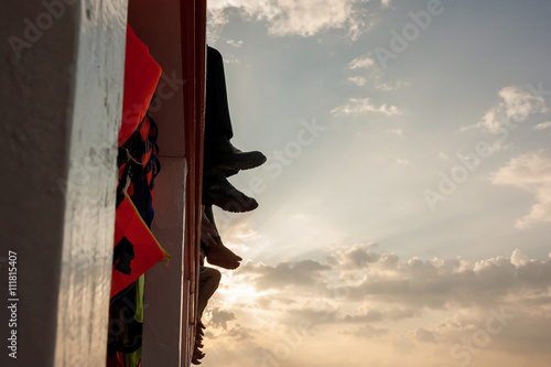 People sit on the ferry, his legs dangling over sea. photo