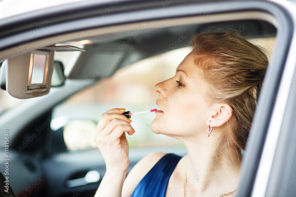 Blonde woman applying make-up in a car Blonde woman applying make-up in a car