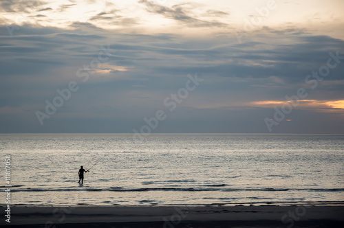 Fishing. Evening shoot of solitary fisherman on an Australian beach.
