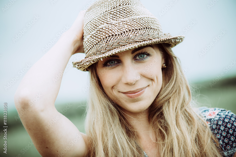 Portrait of pretty cheerful woman wearing white dress and straw hat in sunny warm weather day. Walking at summer park and smiling