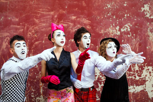 Four mimes looking aside on the background of a red wall.