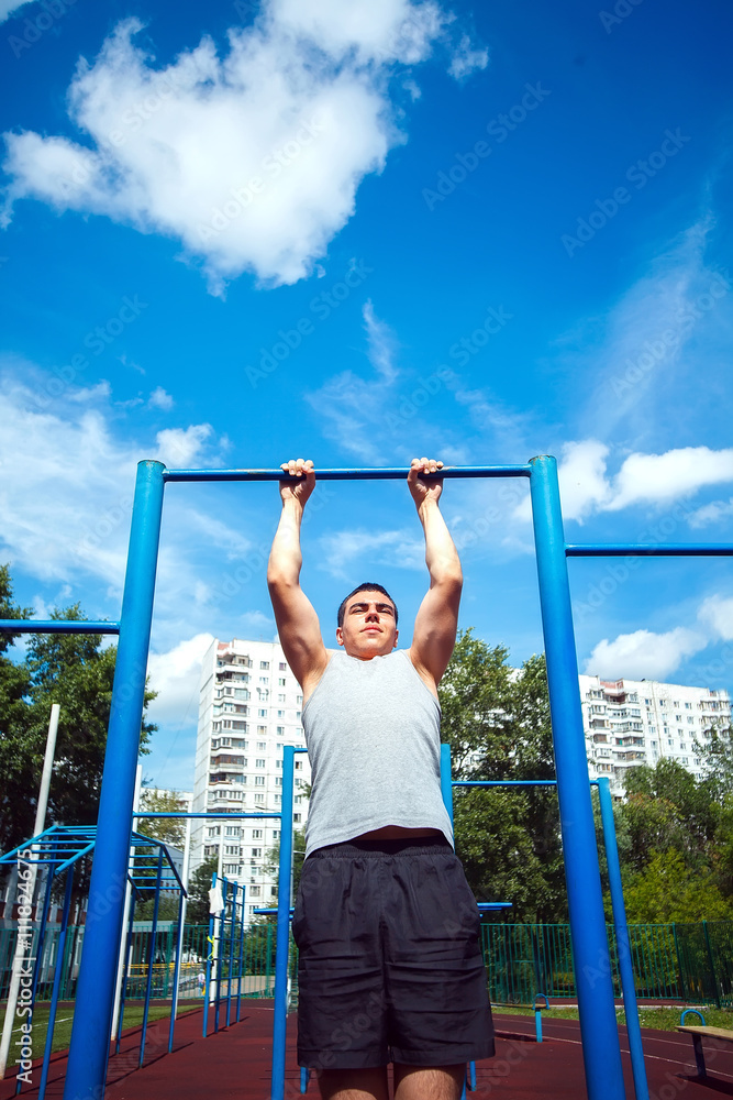 Muscular man doing pull-ups on horizontal bar Muscular man doing pull-ups on horizontal bar