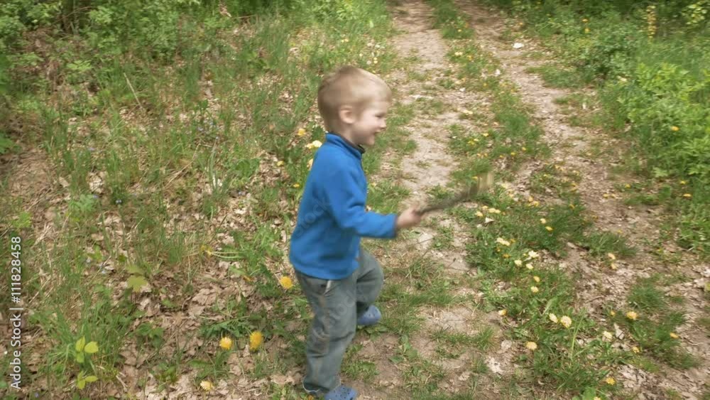 Happy little 3-5 years child boy looks at camera laughs and smiles runs and plays outdoor game with rod. Carefree childhood summer and happiness concept. 4K UHD video footage. Happy little 3-5 years child boy looks at camera laughs and smiles runs and plays outdoor game with rod. Carefree childhood summer and happiness concept. 4K UHD video footage.
