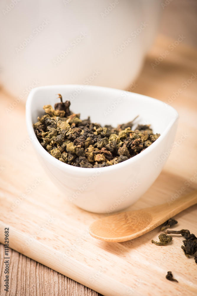 dry tea leaf in ceramic bowl wit whith pot on wood background dry tea leaf in ceramic bowl wit whith pot on wood background