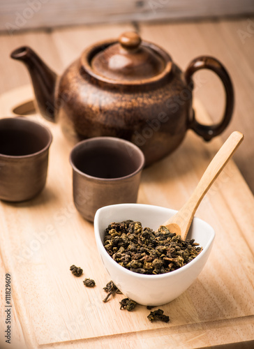  dry tea leaf in ceramic bowl wit pot on wood background