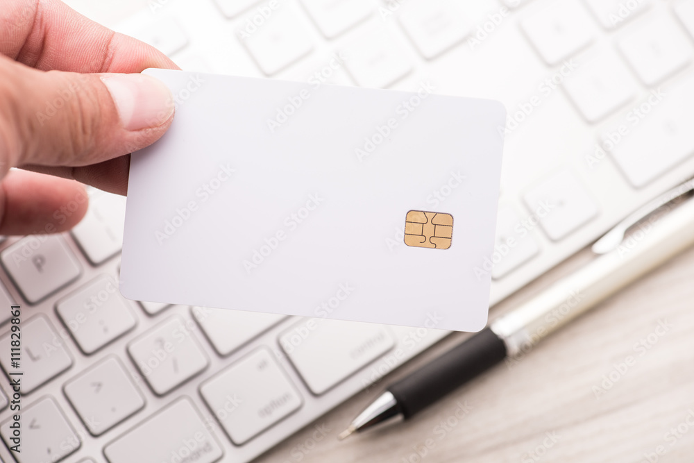 hand holding a white credit card and typing. On-line shopping on hand holding a white credit card and typing. On-line shopping on