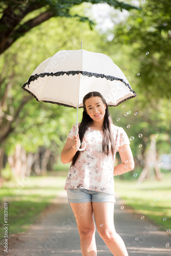 Portrait of beautiful mid adult Asian woman holding umbrella