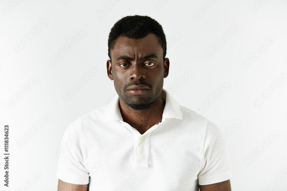 Portrait of angry or annoyed young African American man in white polo shirt  looking at the camera with displeased expression. Negative human  expressions, emotions, feelings. Body language Photos | Adobe Stock