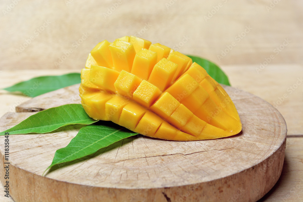 ripe mango with mango leaf in wooden background.