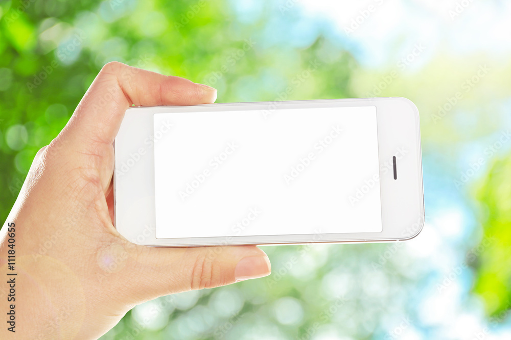 Hand shows mobile smart phone, nature blurred background Hand shows mobile smart phone, nature blurred background