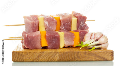 Skewers with slices fresh pork, vegetables, garlic and board isolated.