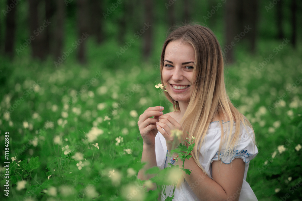 Beautiful young girl close-up in a white shirt, against a background of green forest