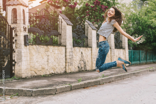 Beautiful and stylish girl with a hat posing on the street and jumping.