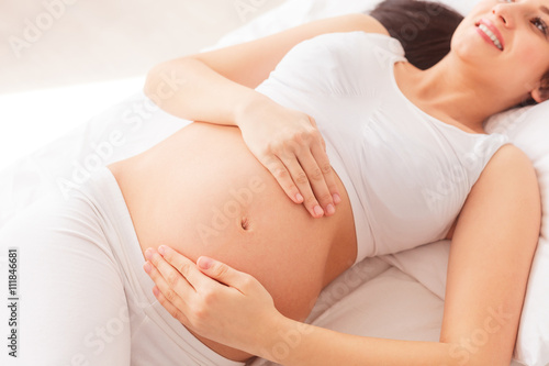 Cheerful pregnant woman is resting at home