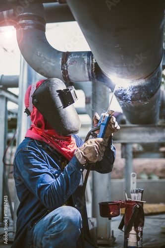 Welder is welding pipe on construction site