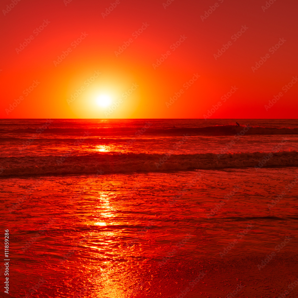 Fantastic evening light. Setting sun over the Pacific ocean colors the sky and waves in red color.