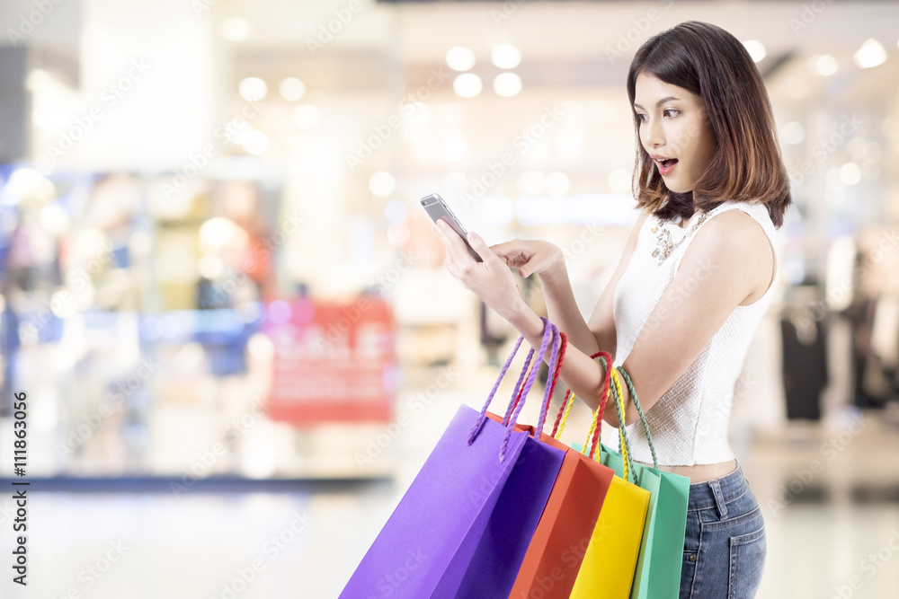 Woman shopping in shopping mall and use mobile phone shopping and find promotion. Woman shopping in shopping mall and use mobile phone shopping and find promotion.