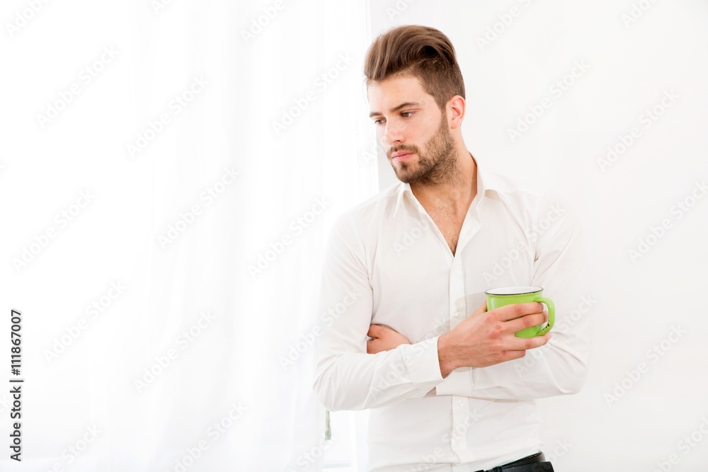 A young adult man at home drinking coffee.. A young adult man at home drinking coffee..