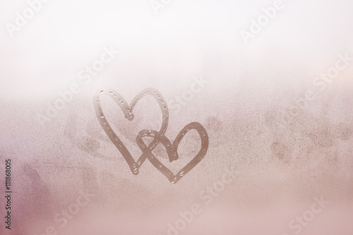Love hearts painted on glass. The window is fogged 