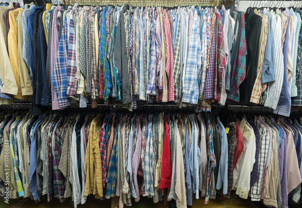 Used Men shirts hanging at clothes rails of a thrift store