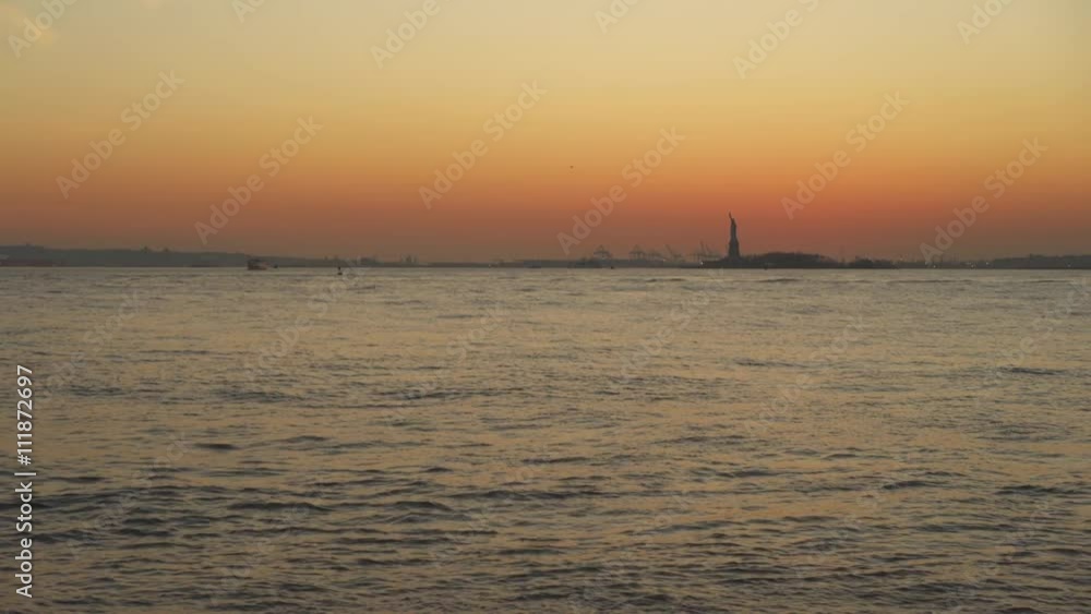 Statue of Liberty in the distance across Hudson River at evening hours sunset.
Statue of Liberty in the distance across Hudson River at evening hours sunset.