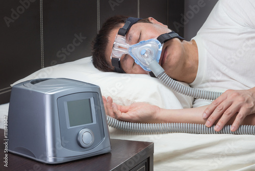 Asian man with sleep apnea using CPAP machine